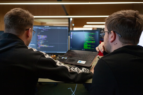 IT guys looking at a coding program on a laptop and monitor